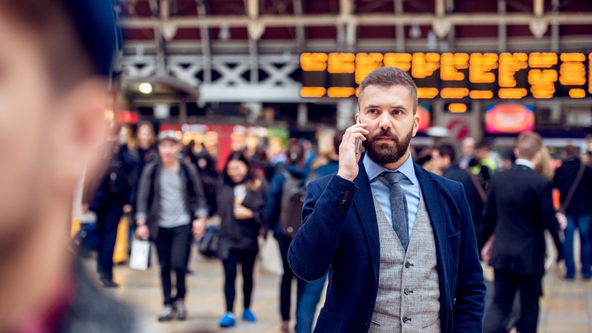 Busy businessman with smartphone, making phone call, crowded sta